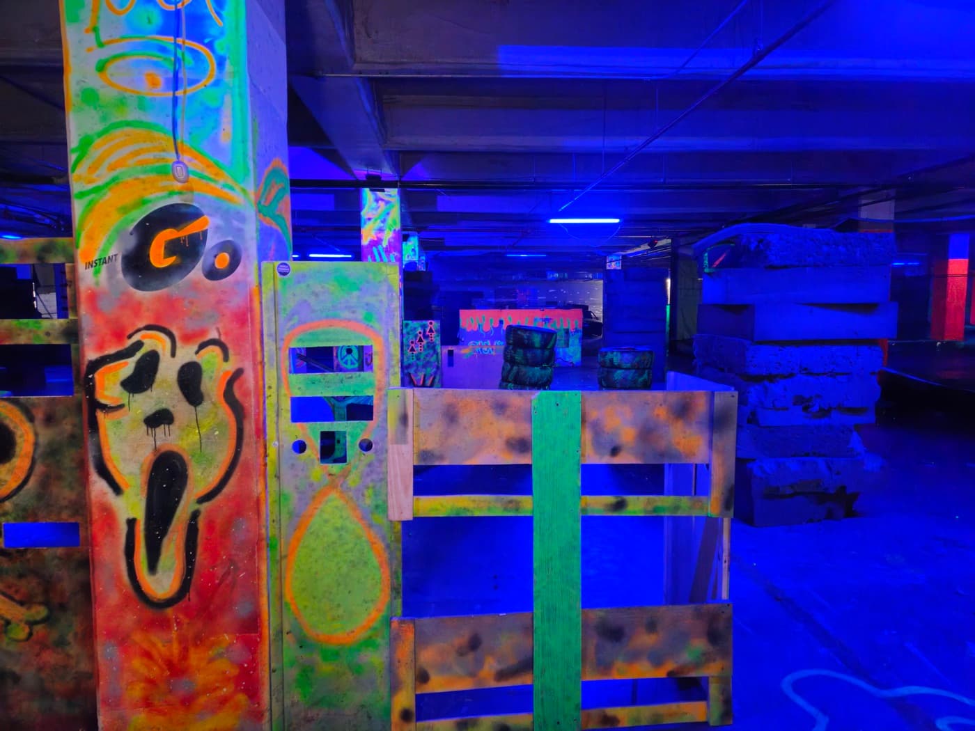 Barricadas con grafitis fluorescentes bajo luz negra — Sede Outlet Factory